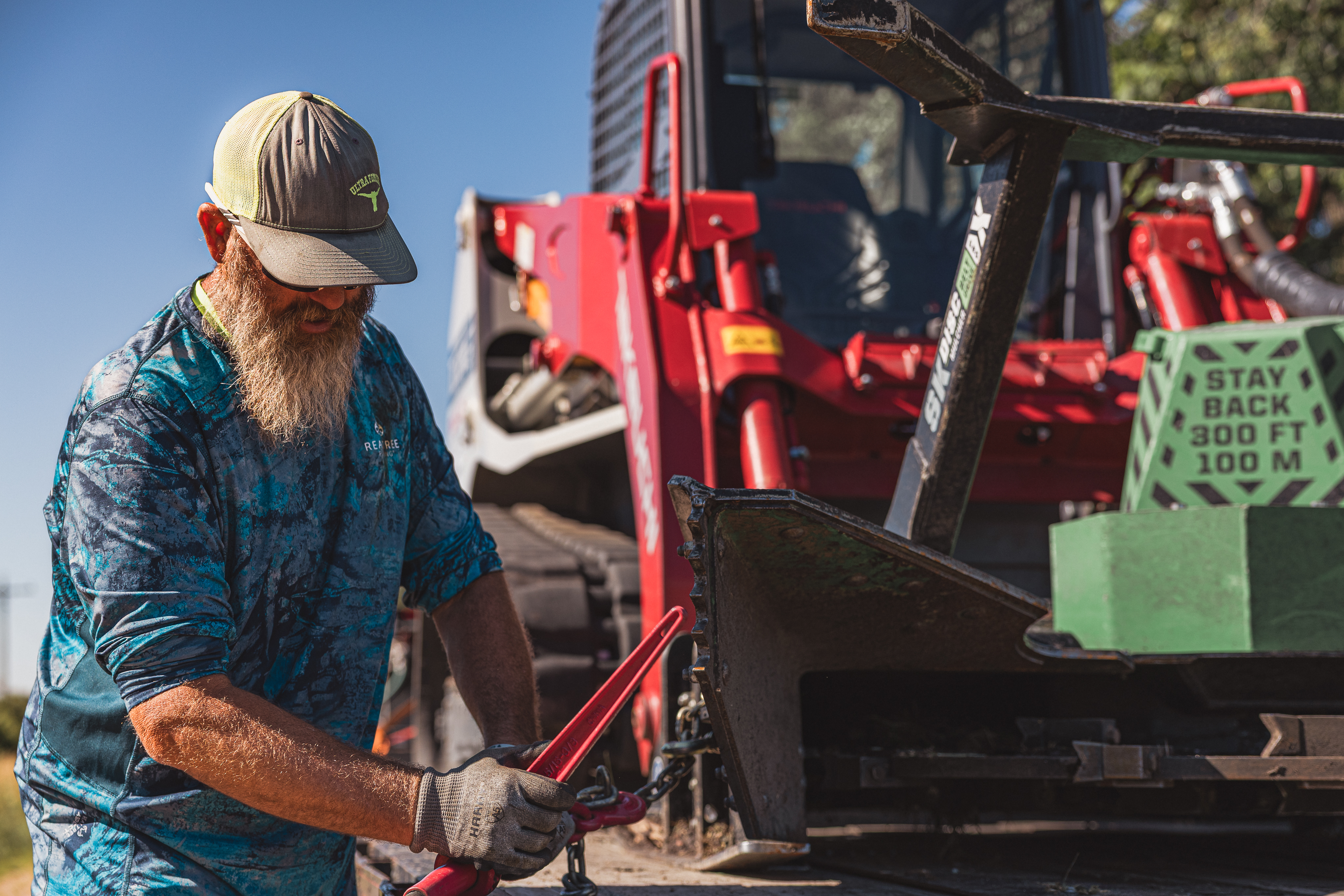 person setting up a disc mulcher on a skid steer