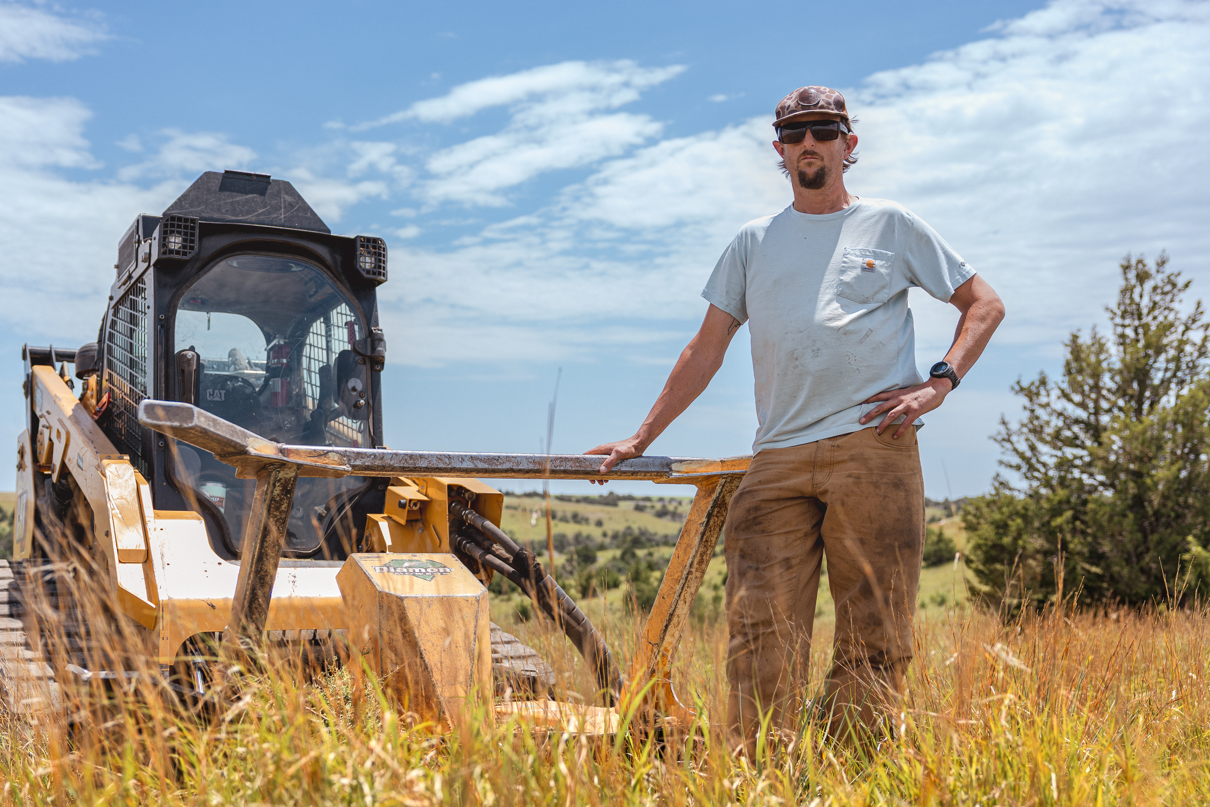 person standing in front of a skid steer disc mulcher