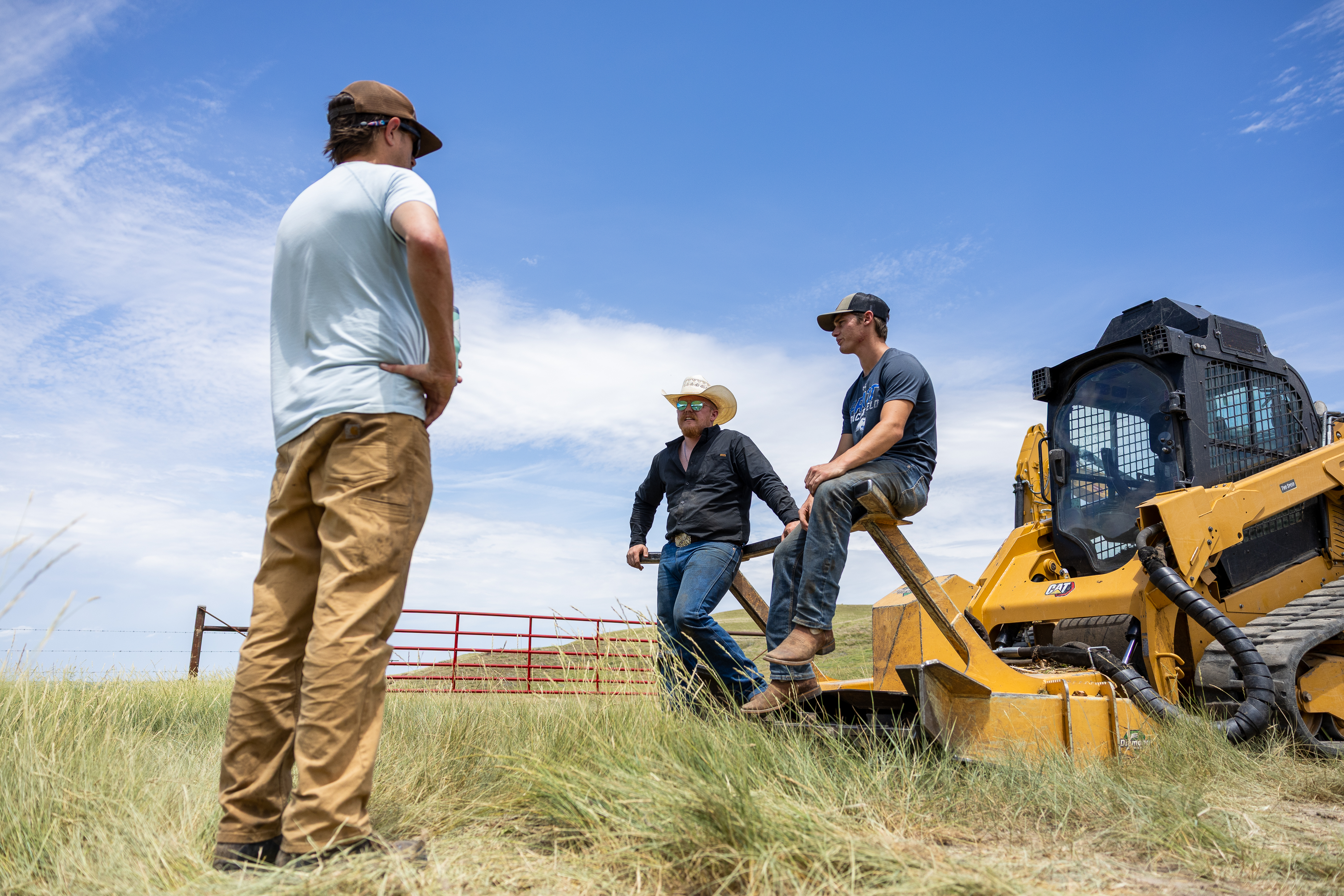 three people standing around a skid steer disc mulcher